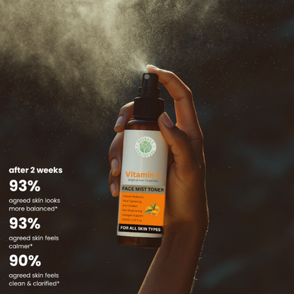 Hand holding a bottle of Vitamin C face mist toner with product details on a dark background